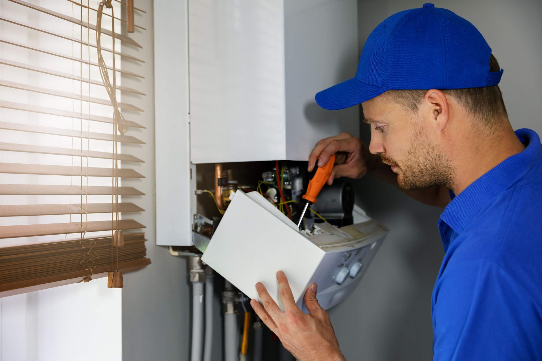 dreamstime_m_153386372 House gas heating boiler maintenance and repair service. worker in blue uniform